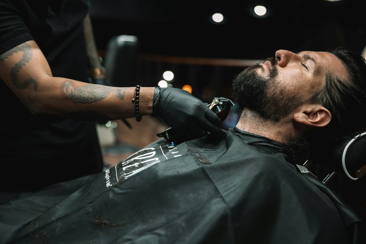 Barbero haciendo un corte a un cliente en su silla