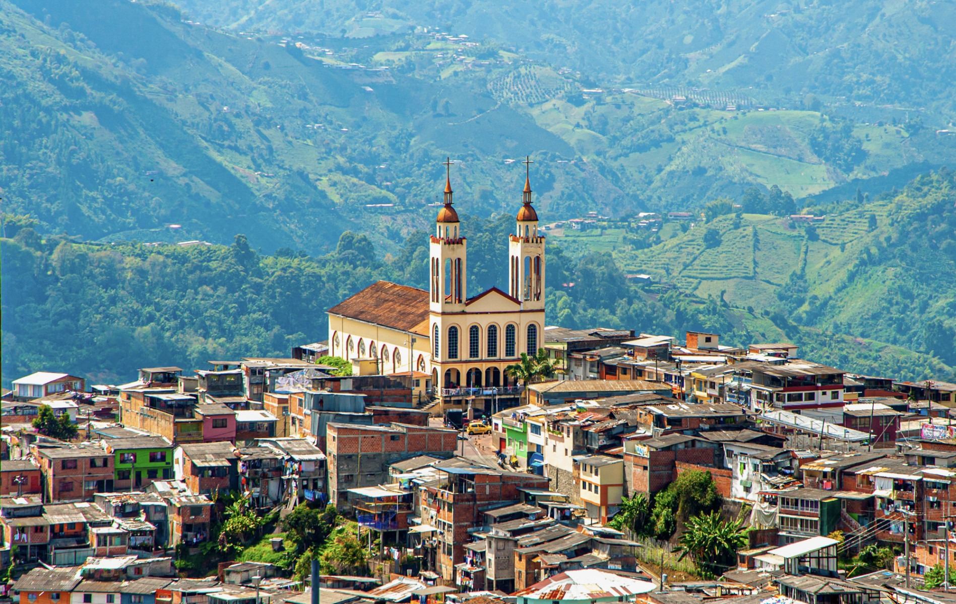 Un barrio de Manizales en la ladera, con su iglesia de dos torres y la cordillera al fondo