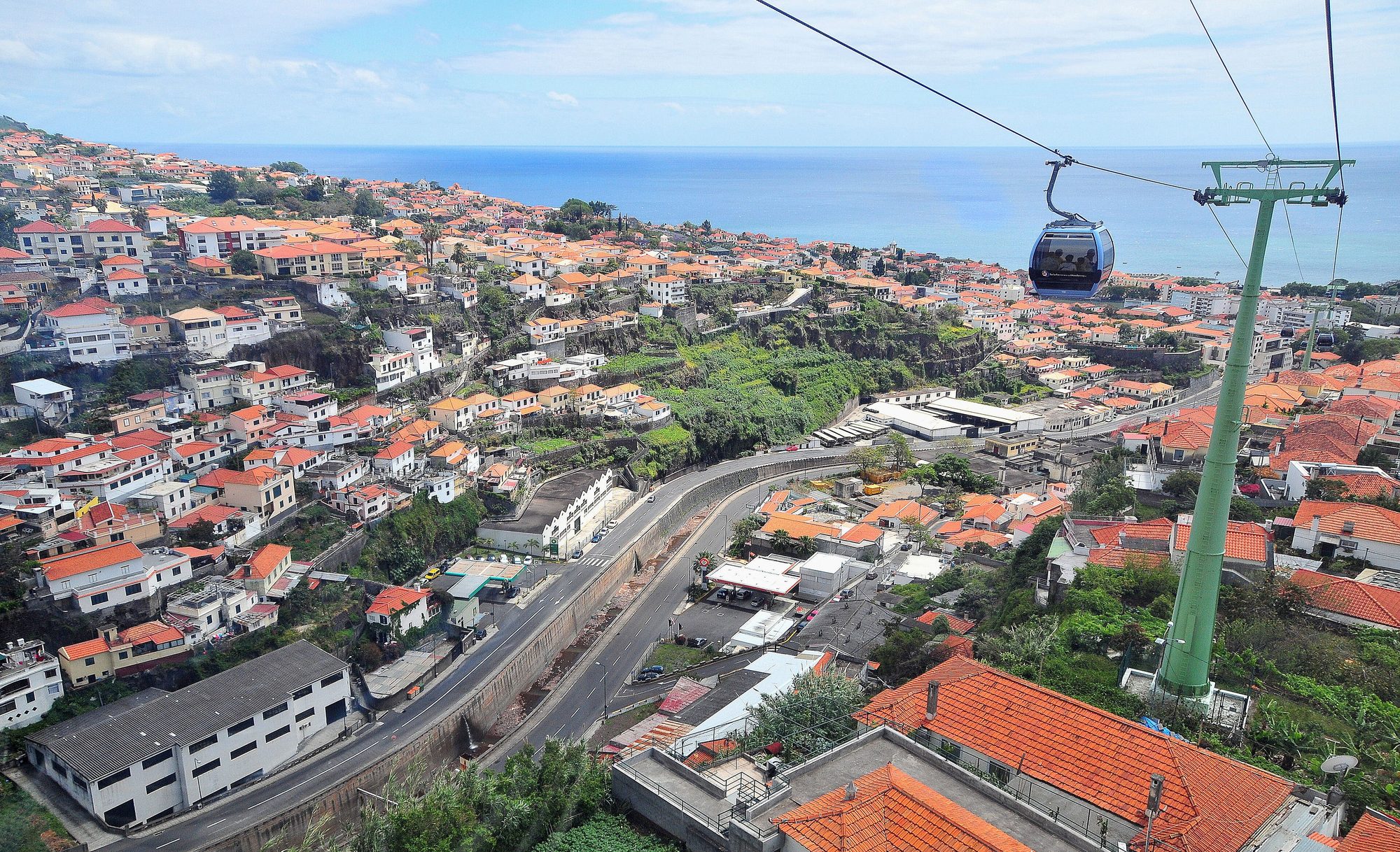 O Funchal visto do teleférico, com os telhados laranja, a encosta verde e o mar ao fundo