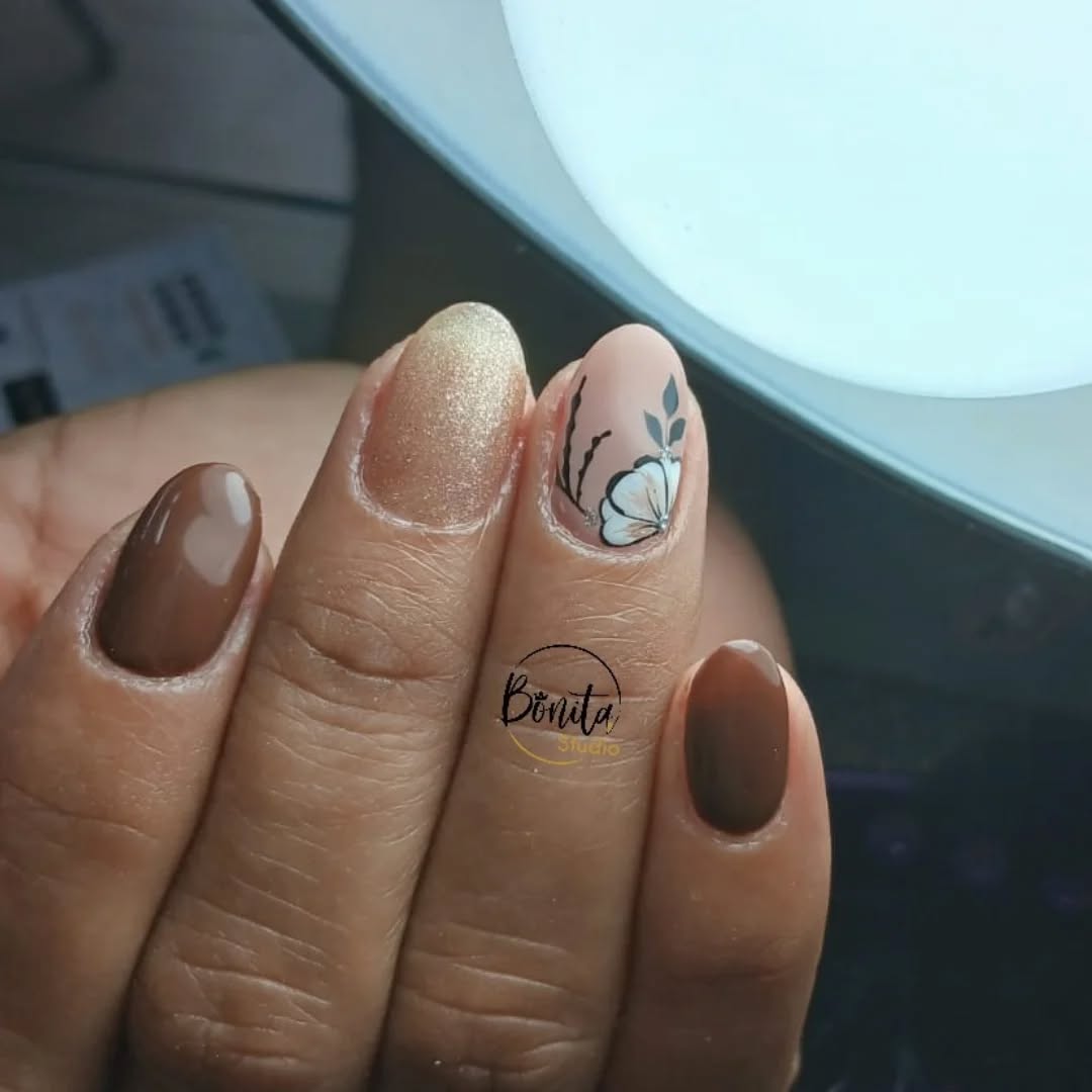 Uñas en café brillante, dorado escarchado y una flor pintada a mano