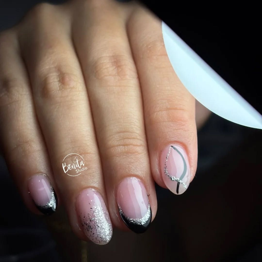 Uñas rosadas con puntas negras, brillo plateado y líneas finas sobre fondo oscuro